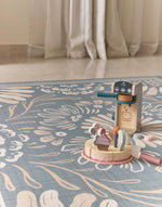 Wooden toy set on a floral-patterned rug with curtains in the background